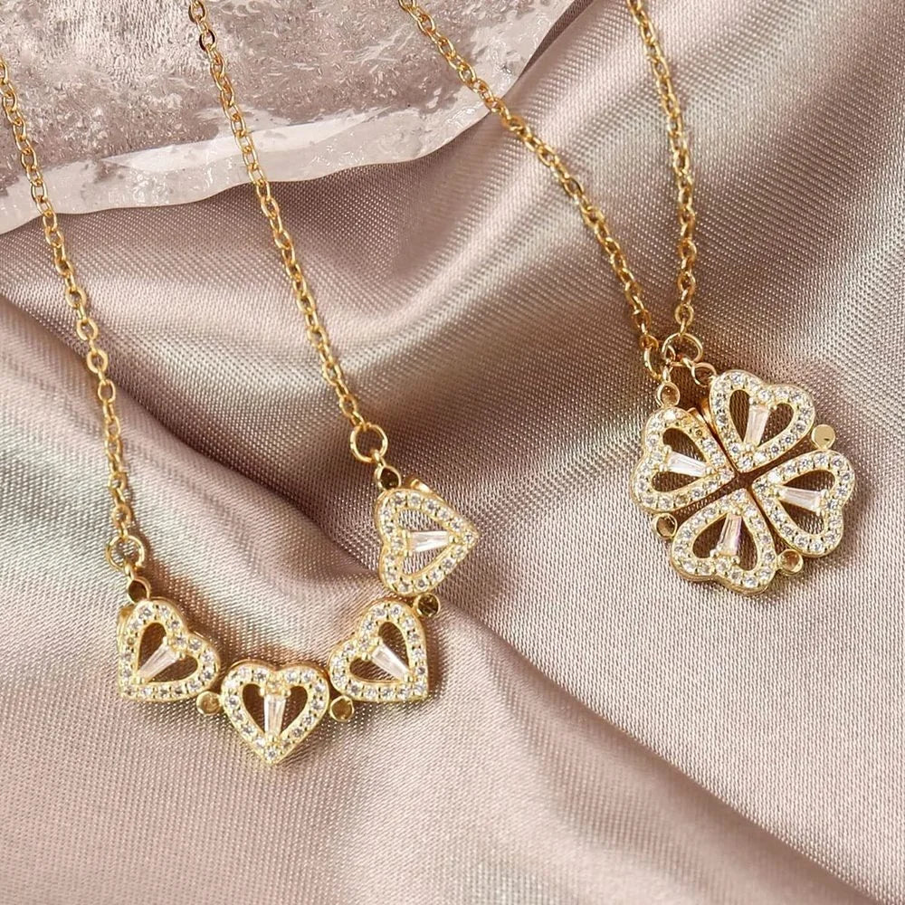 Collier pendentif réversible cœurs trèfle en acier doré et pierres scintillantes, illustrant les deux configurations sur un tissu satiné beige, Maison Mercier.