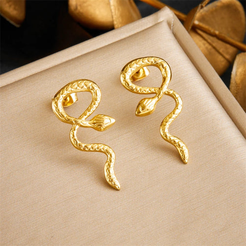 Détail d'une collection de boucles d'oreilles variées en acier inoxydable doré, présentant des designs géométriques, perlés et organiques, Maison Mercier.