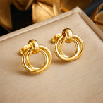 Détail d'une collection de boucles d'oreilles variées en acier inoxydable doré, présentant des designs géométriques, perlés et organiques, Maison Mercier.