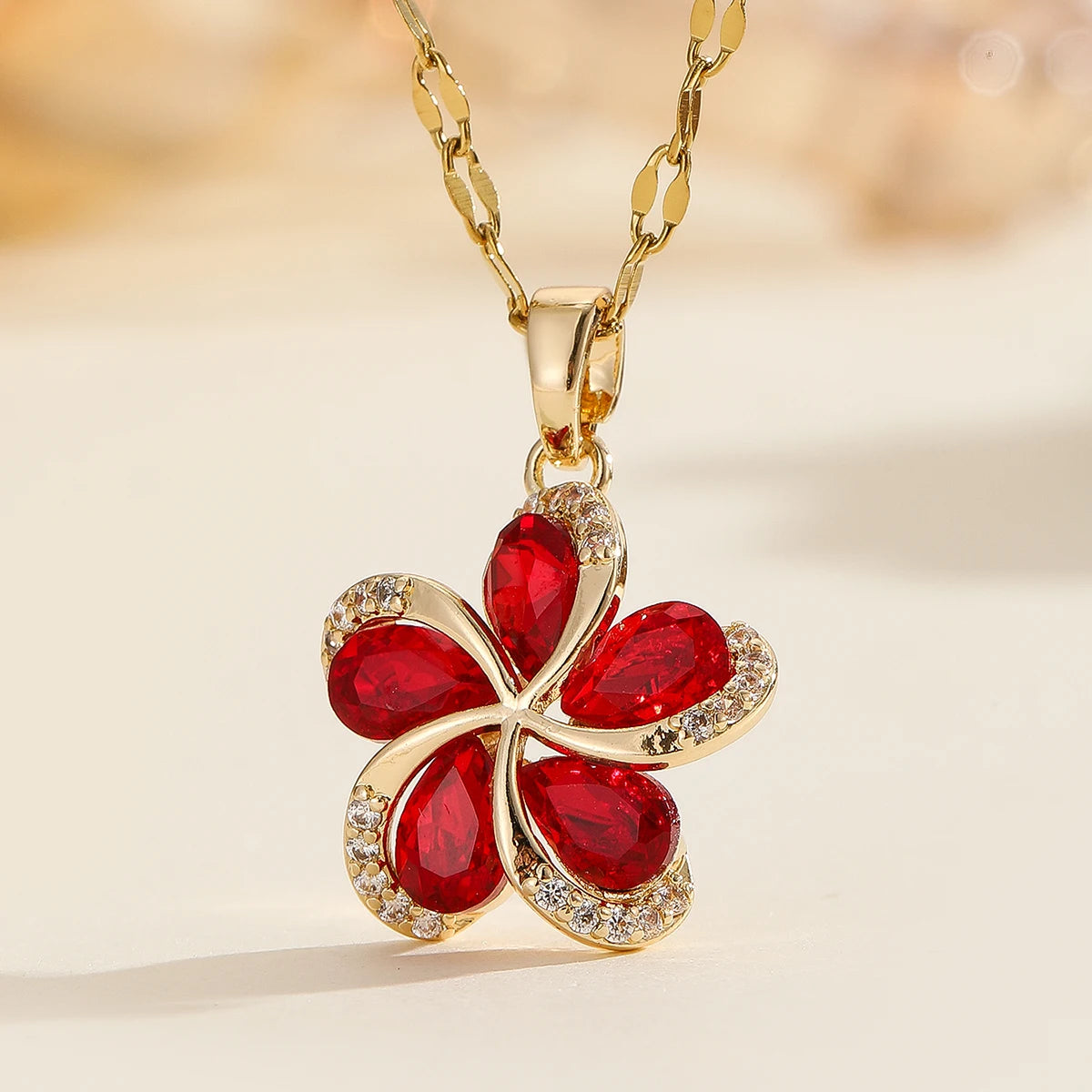 Vue d'ensemble de trois Colliers Pendentifs Floraux Maison Mercier, ornés de zircons blancs, verts et rouges, en acier doré.