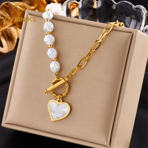 Détail d'un collier pendentif cœur 'Love' en acier inoxydable doré poli, posé sur un tissu élégant, Maison Mercier.