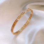 Bracelet jonc doré avec motif Méandre, capturant la lumière sur sa surface polie, symbolisant l'élégance intemporelle, Maison Mercier.