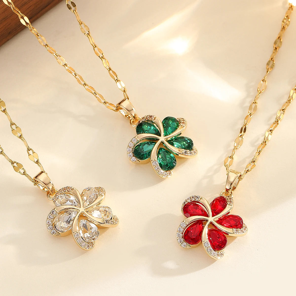 Vue d'ensemble de trois Colliers Pendentifs Floraux Maison Mercier, ornés de zircons blancs, verts et rouges, en acier doré.