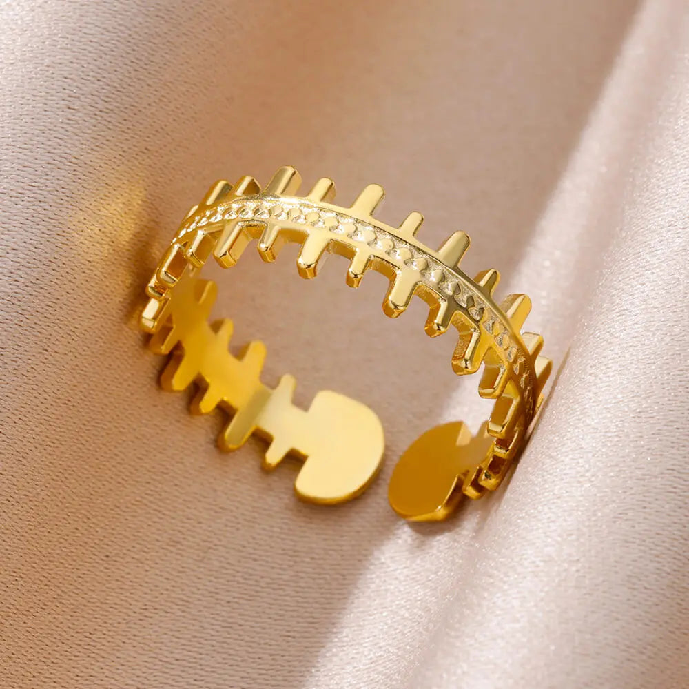 Photographie d'une bague ajustable dorée en acier inoxydable, au design original en forme d'arête de poisson stylisée, Maison Mercier.