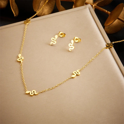 Détail d'une parure collier et puces d'oreilles serpent en acier doré, Maison Mercier.