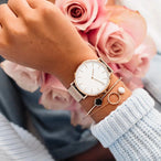 Montre féminine Maison Mercier, cadran noir épuré, bracelet maille milanaise finition or rose, portée au poignet avec un bracelet délicat à perles dorées.