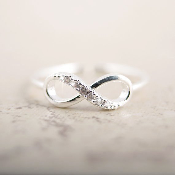 Détail d'une bague infini ajustable en finition argentée, ornée d'oxydes de zirconium scintillants, Maison Mercier.