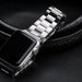 Détail d'un bracelet de montre à maillons classiques en acier inoxydable brossé argenté, fixé sur une montre connectée, posé sur un fond en cuir grainé, Maison Mercier.