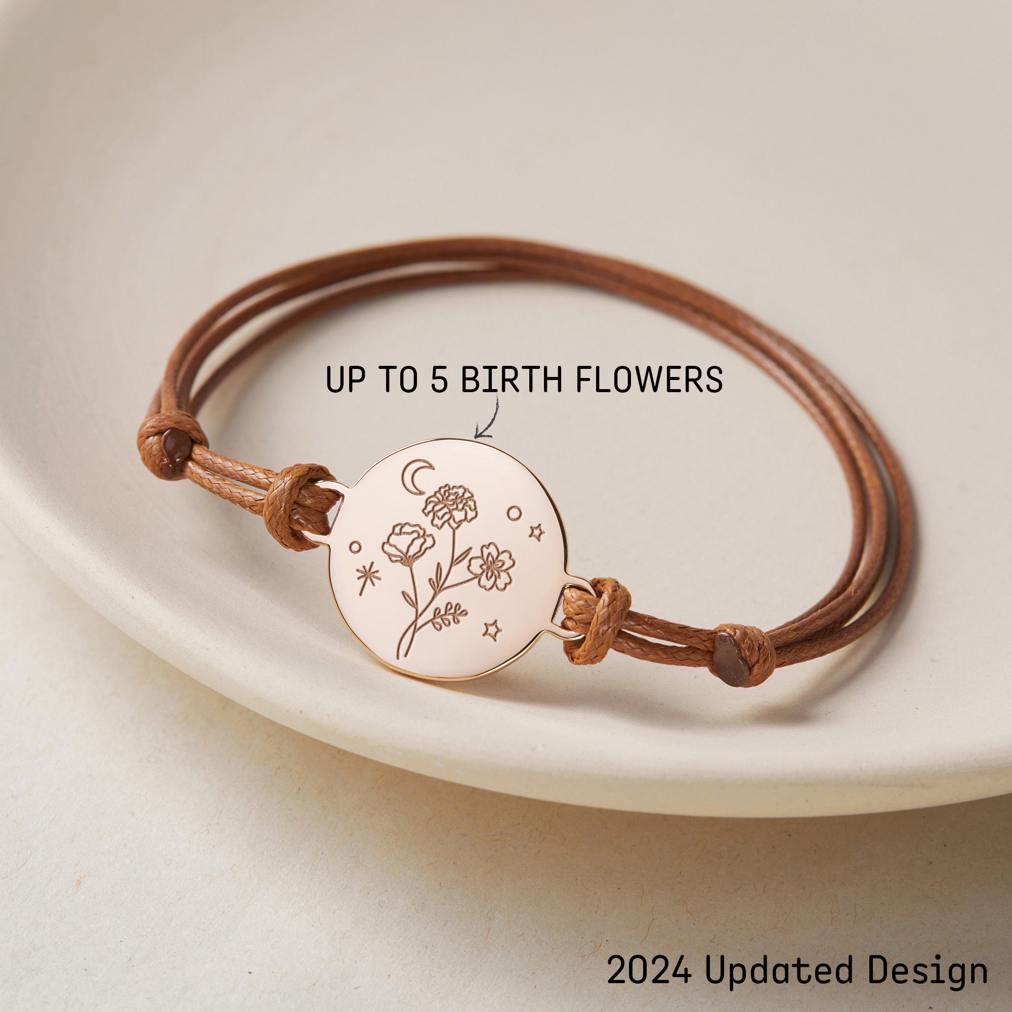 Bracelet cordon ajustable avec médaillon plaqué or gravé de fleurs de naissance, un croissant de lune et des étoiles, sur fond clair, avec texte "UP TO 5 BIRTH FLOWERS" indiquant la personnalisation.