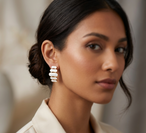 Portrait d'une femme élégante portant les boucles d'oreilles pendantes à maillons oblongs émaillés blanc pur, finition or précieux, Maison Mercier.