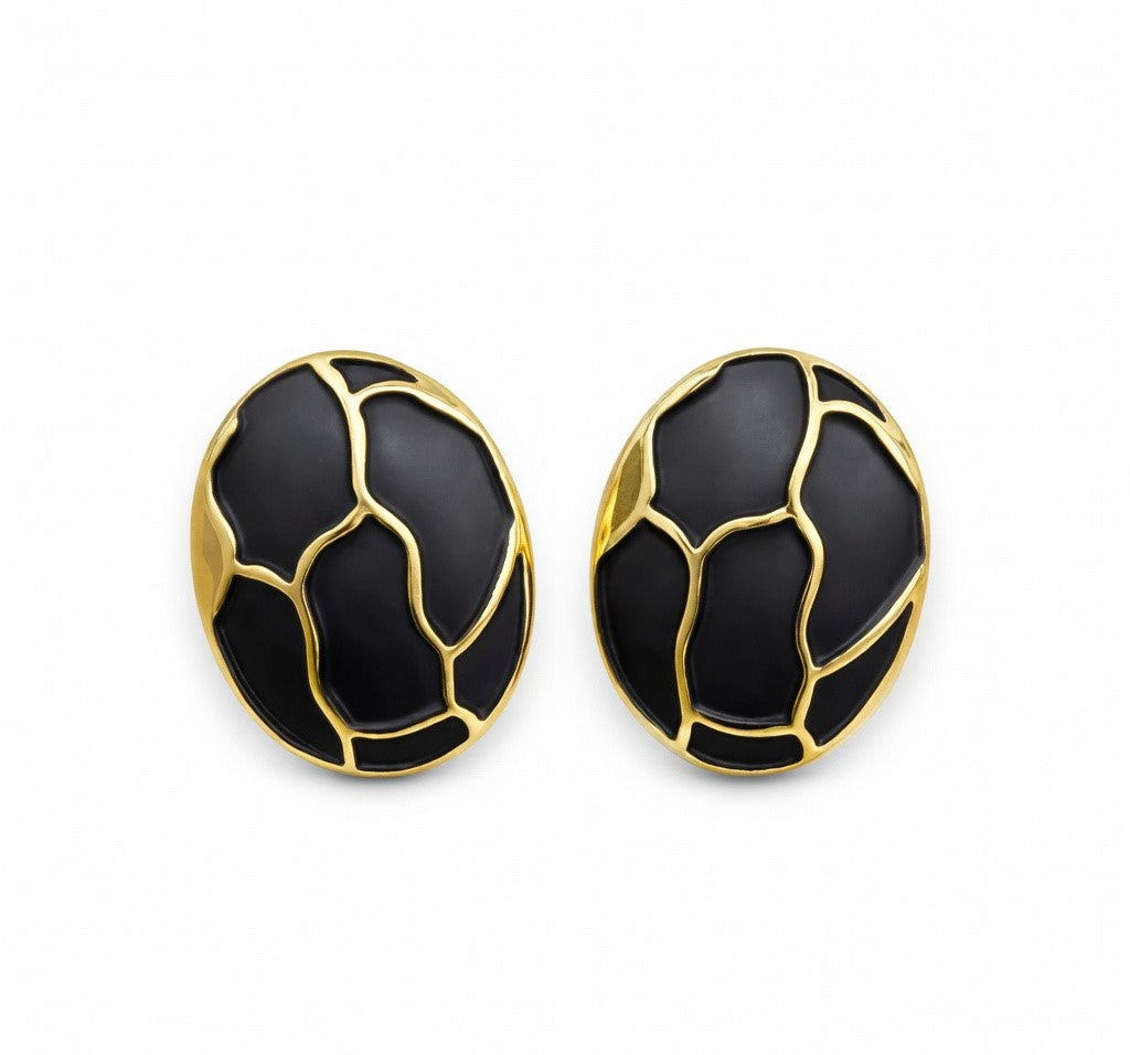 Vue de dessus d'une paire de boucles d'oreilles ovales en émail noir profond et finition or patiné, motif organique, sur fond blanc pur, Maison Mercier.
