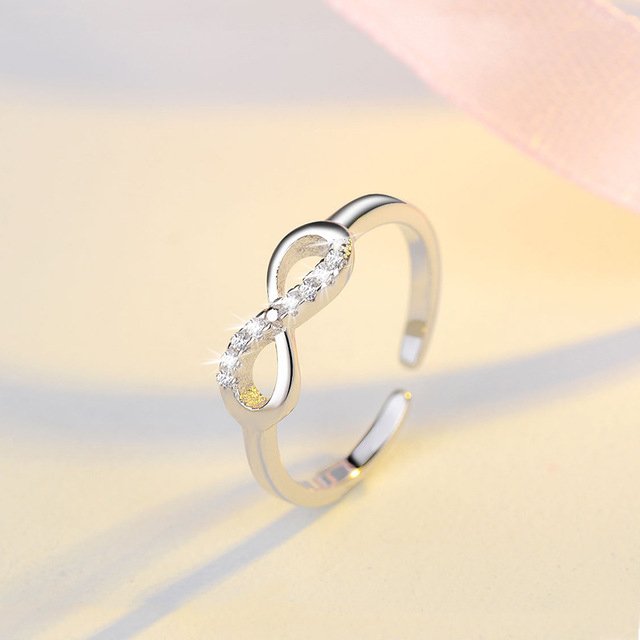 Détail d'une bague infini ajustable en finition argentée, ornée d'oxydes de zirconium scintillants, Maison Mercier.