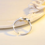 Détail d'une bague infini ajustable en finition argentée, ornée d'oxydes de zirconium scintillants, Maison Mercier.