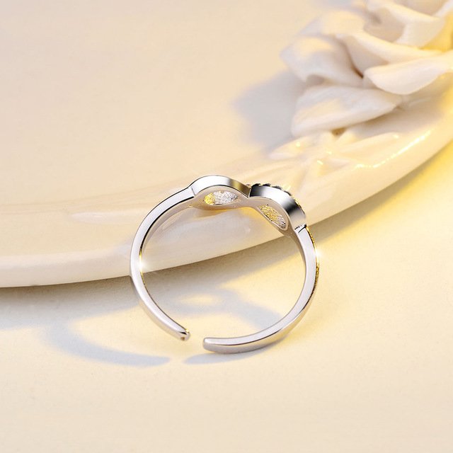 Détail d'une bague infini ajustable en finition argentée, ornée d'oxydes de zirconium scintillants, Maison Mercier.