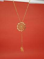 Collier pendentif toile d'araignée et araignée en plaqué or 18 carats, suspendu sur un fond rouge vif, Maison Mercier.