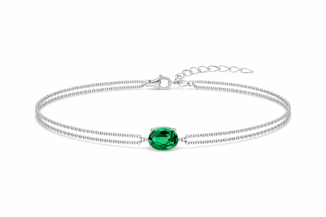 Détail d'un bracelet double chaîne en argent rhodié orné d'une émeraude ovale facettée, Maison Mercier.
