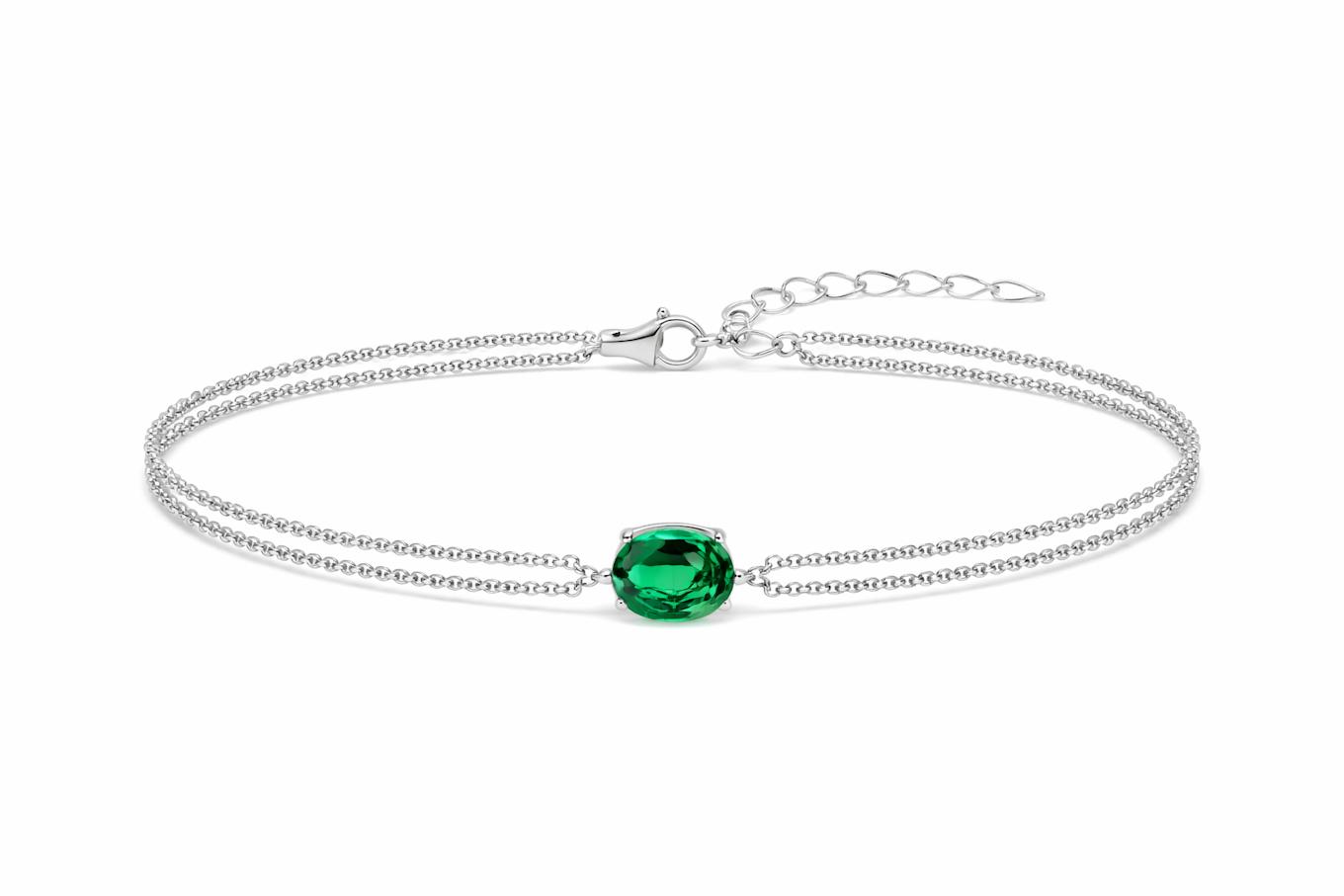 Détail d'un bracelet double chaîne en argent rhodié orné d'une émeraude ovale facettée, Maison Mercier.
