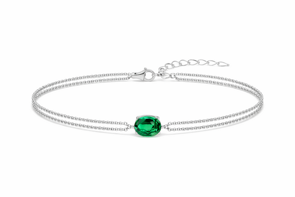 Détail d'un bracelet double chaîne en argent rhodié orné d'une émeraude ovale facettée, Maison Mercier.