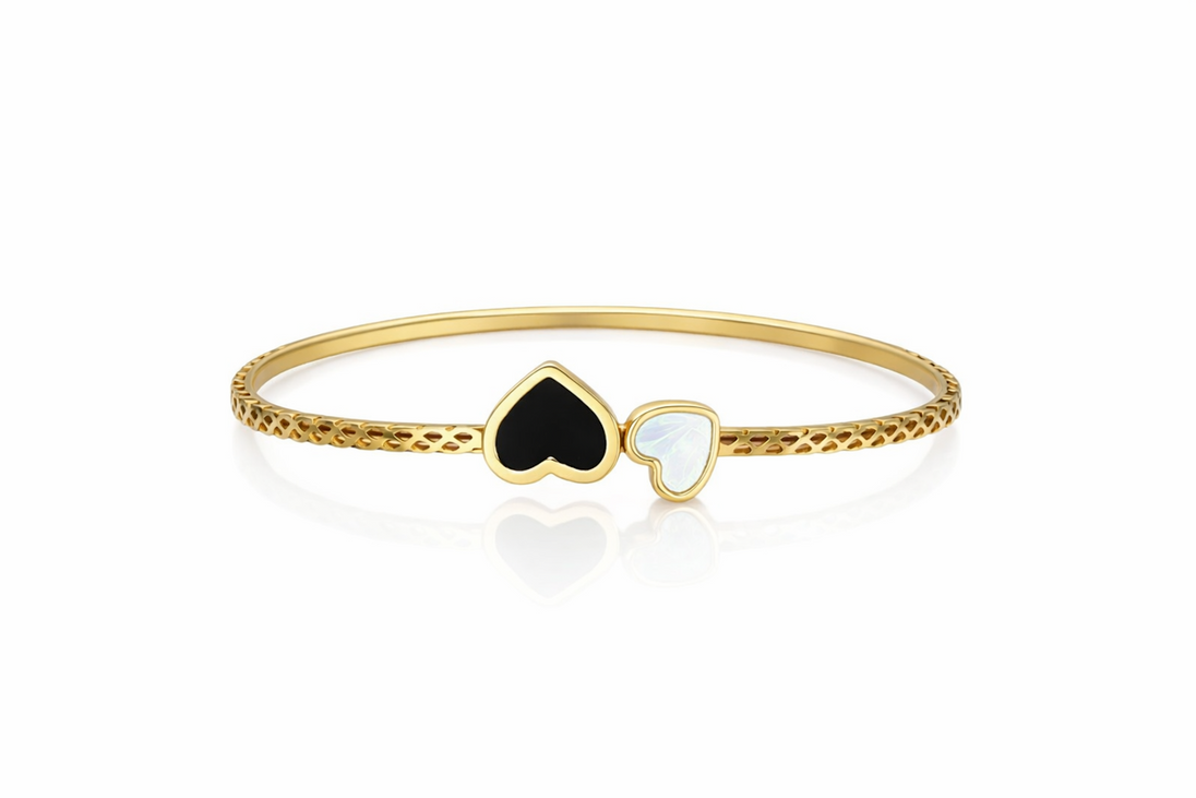 Détail d'un bracelet jonc rigide doré, orné de cœurs en onyx et nacre irisée, avec un motif alvéolé délicat, Maison Mercier.
